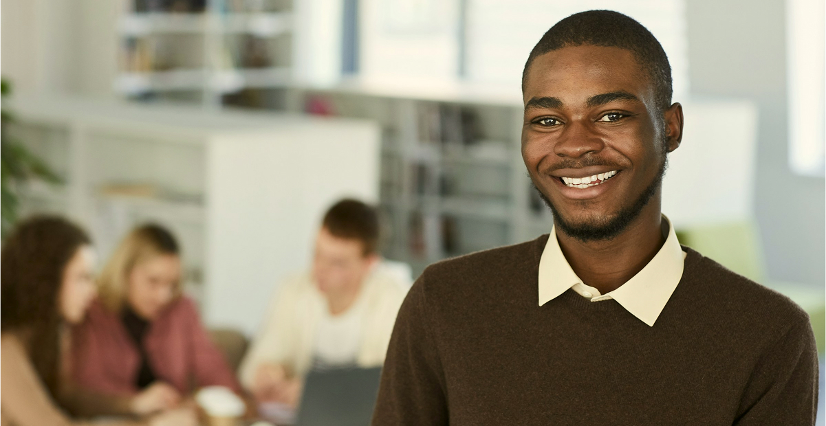 A support agent smiling, with colleagues working behind