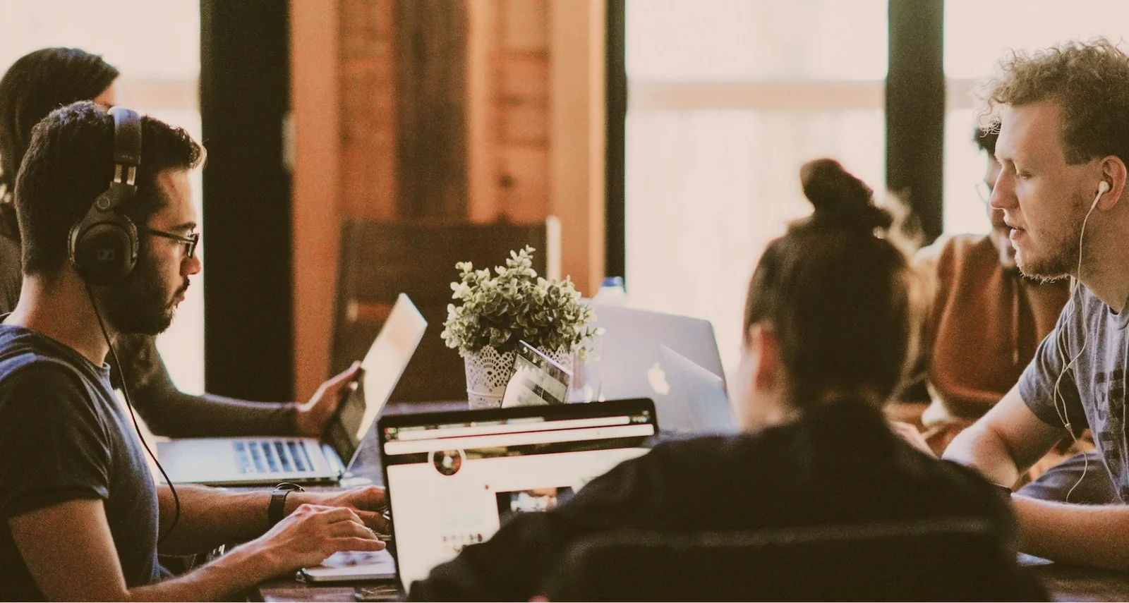 People wearing headsets working on laptops at a shared table