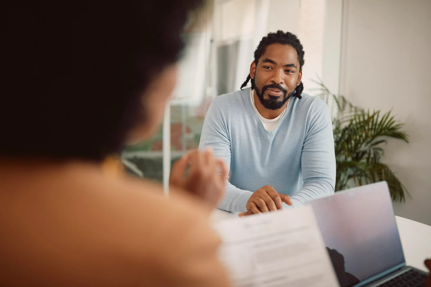 Man at a desk in a meeting, seen past a colleague