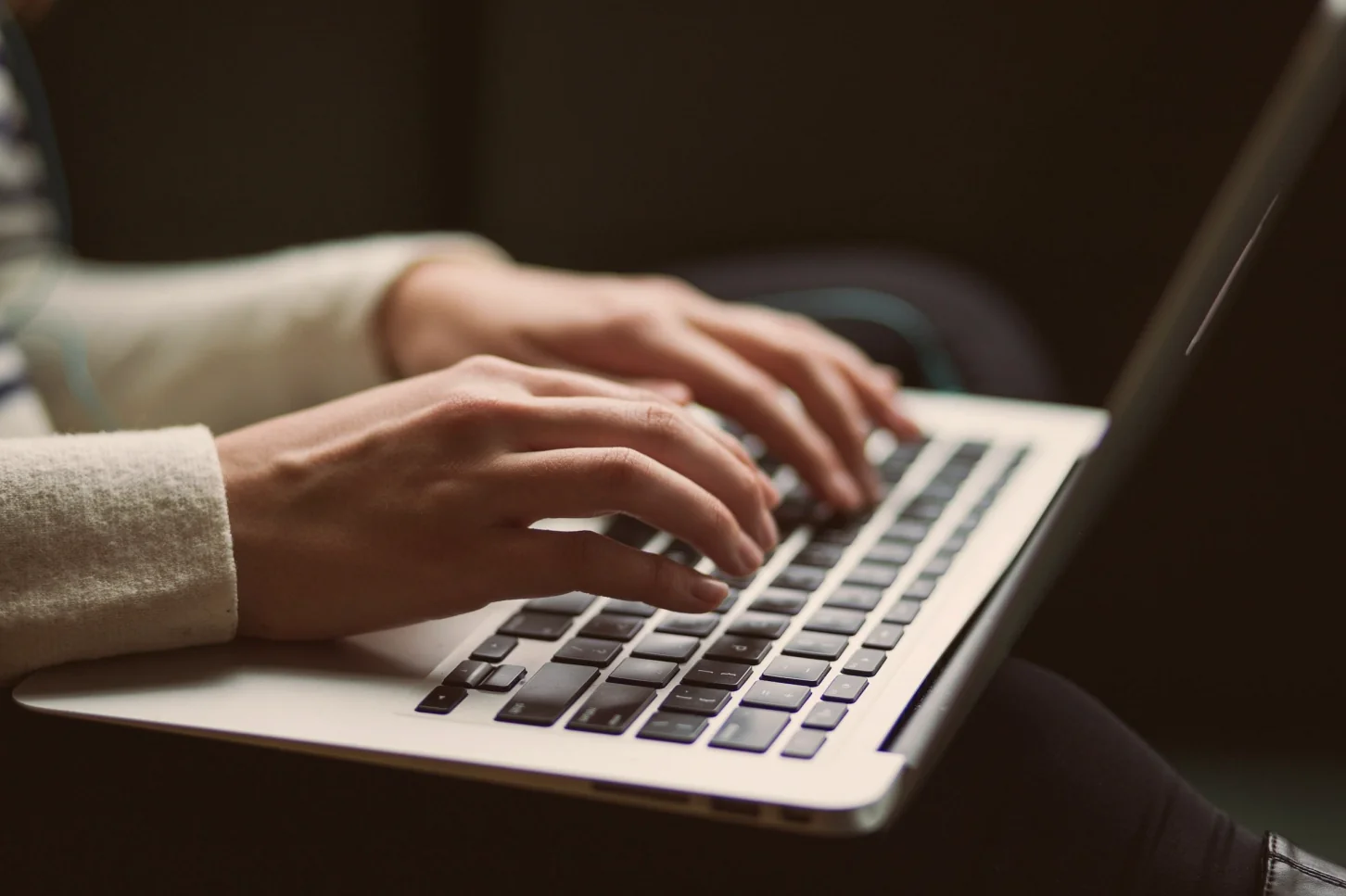 Close-up of hands typing on a laptop