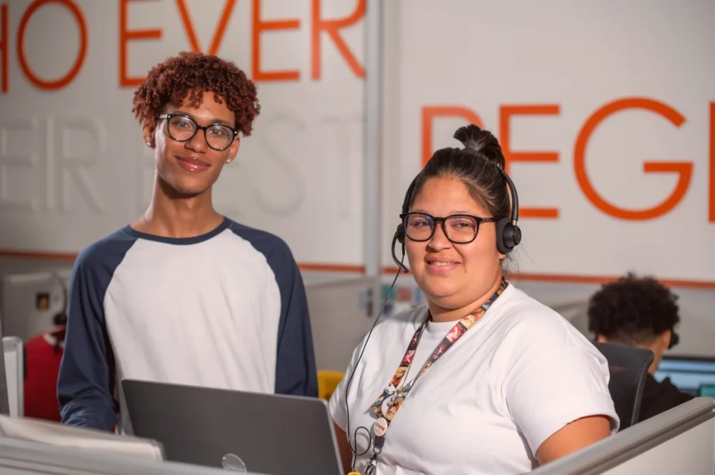Two smiling agents at a computer, one wearing a headset