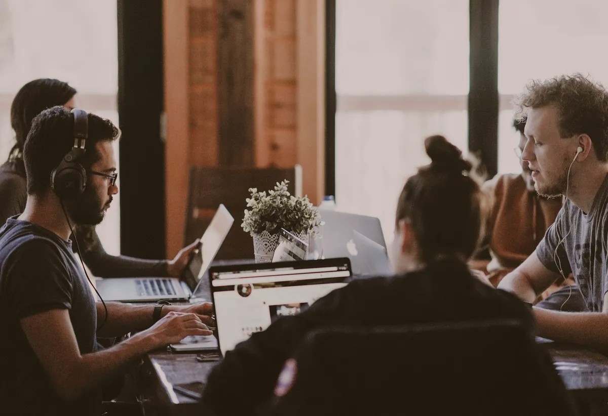 People wearing headsets working on laptops at a shared table