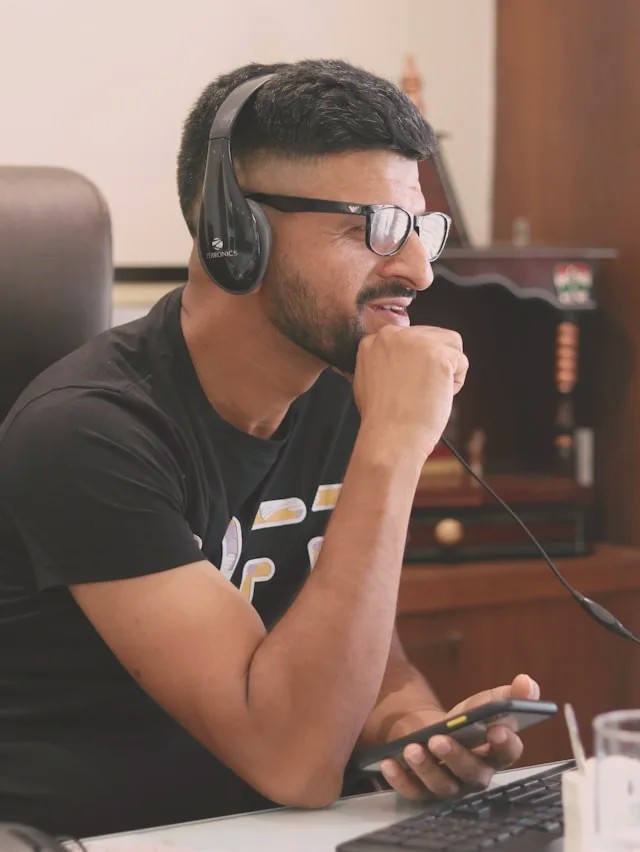 Man with a headset and glasses thinking at his desk