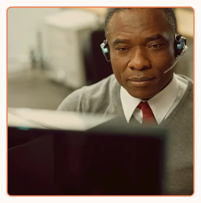 A senior support agent with a headset at a workstation
