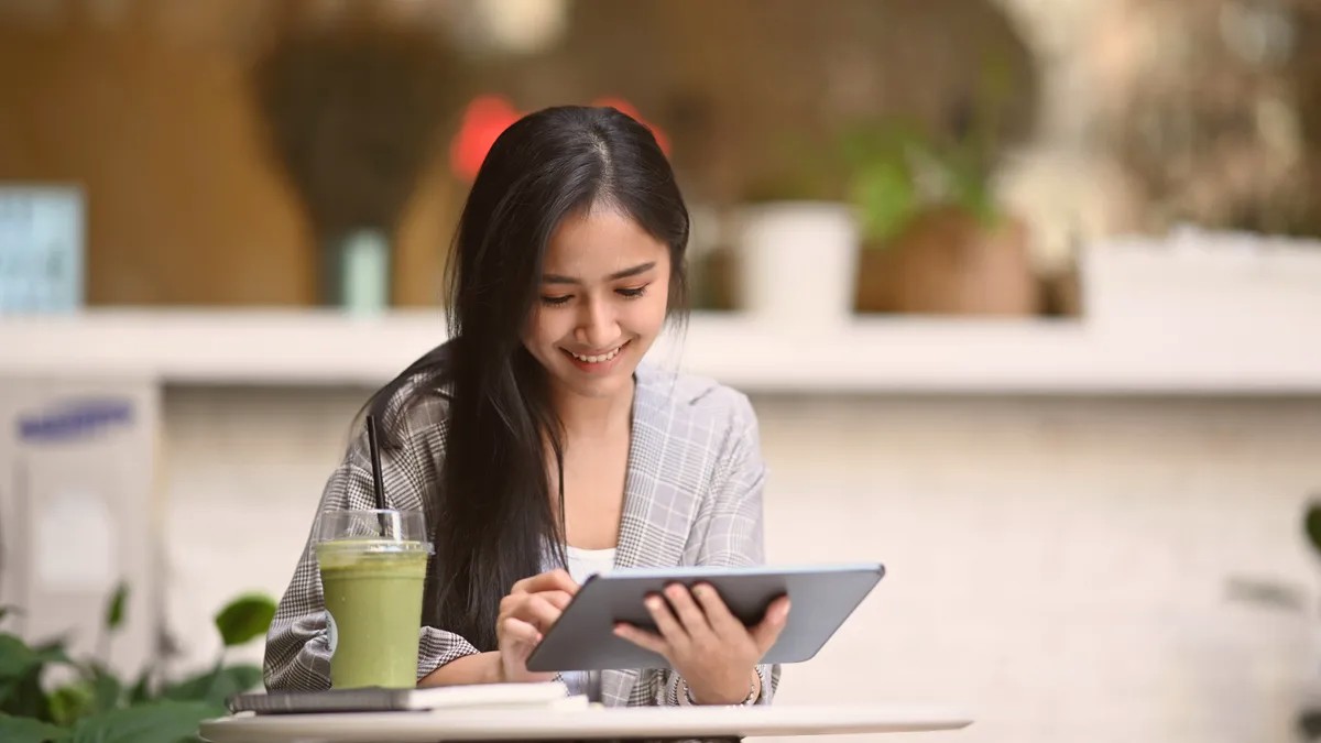 Young woman smiling at a tablet at a table