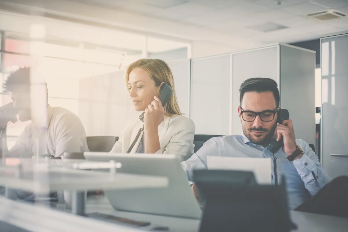 A woman and a man on the phone at desks in an open-plan office
