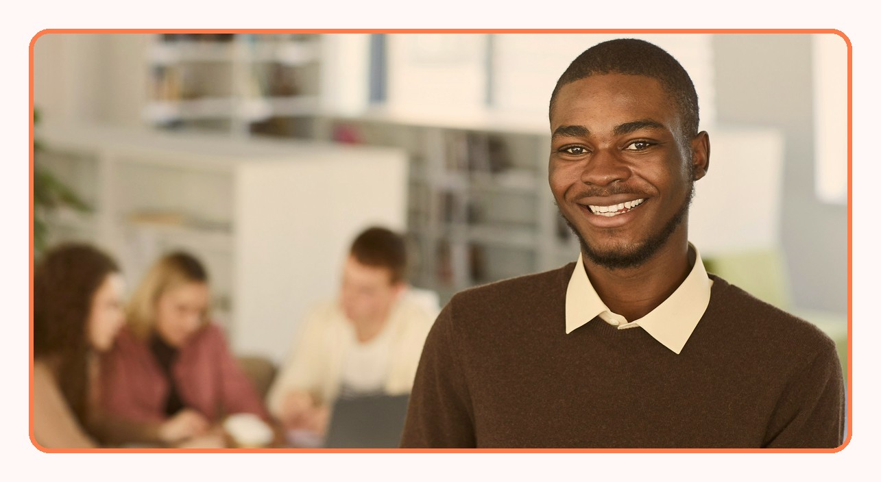 A support agent smiling, with colleagues working behind