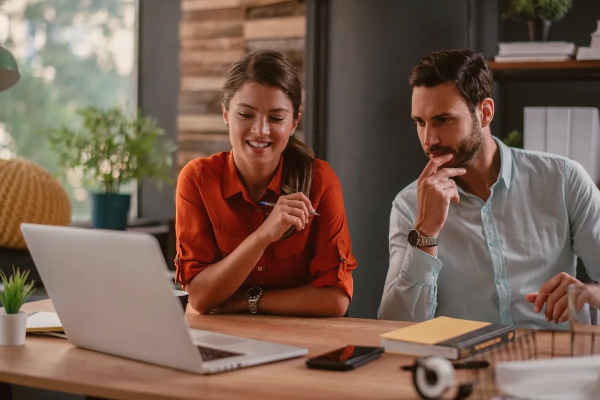 A woman and a man looking at a laptop together at a desk
