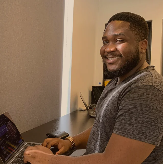 Smiling man typing on a laptop at a desk