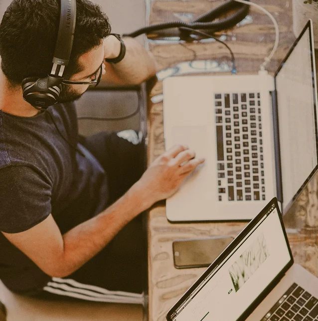 Man wearing a headset typing on a laptop