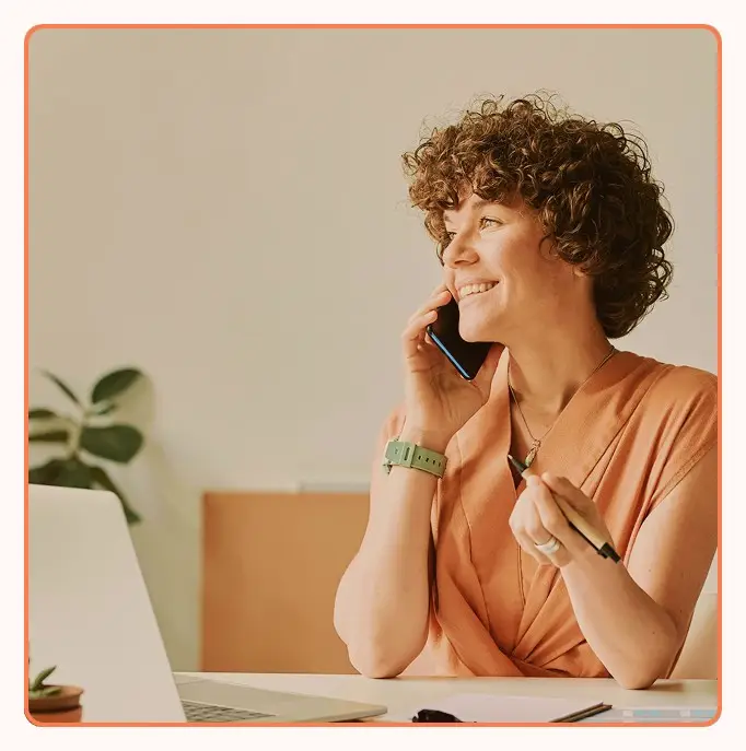 An agent smiling during a phone call at her desk