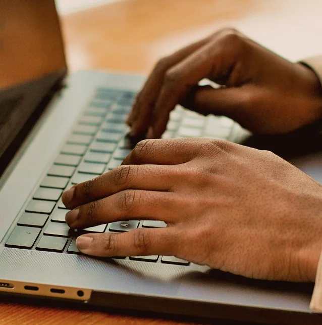 Close-up of hands typing on a laptop keyboard