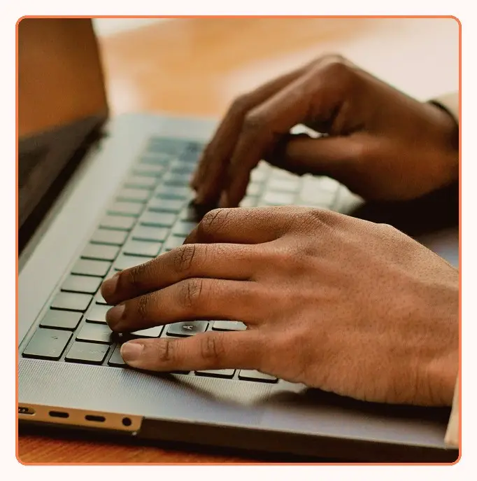 Hands typing on a laptop keyboard, seen from above