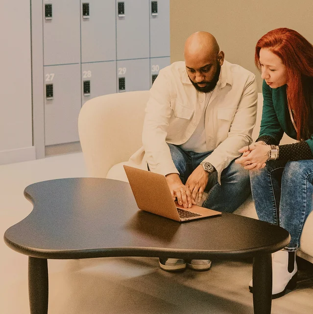 A man and a woman looking at a laptop on a sofa