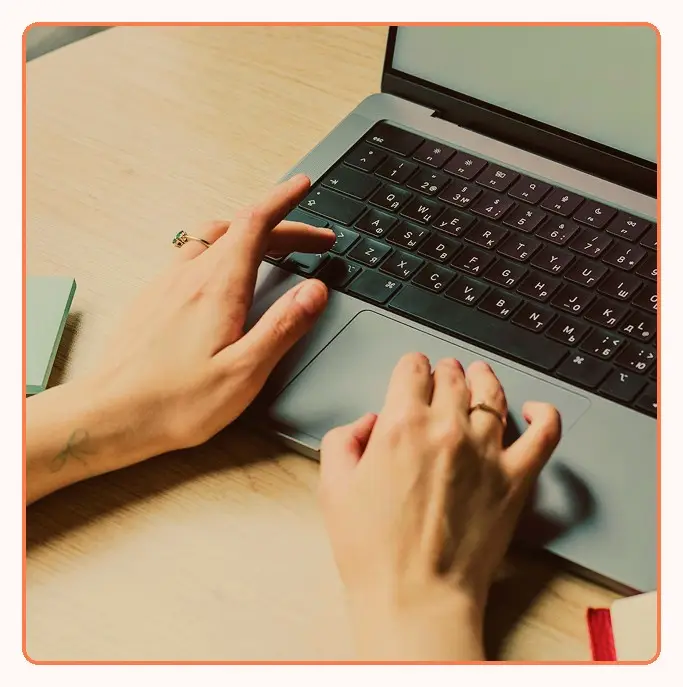Hands working on a laptop at a desk