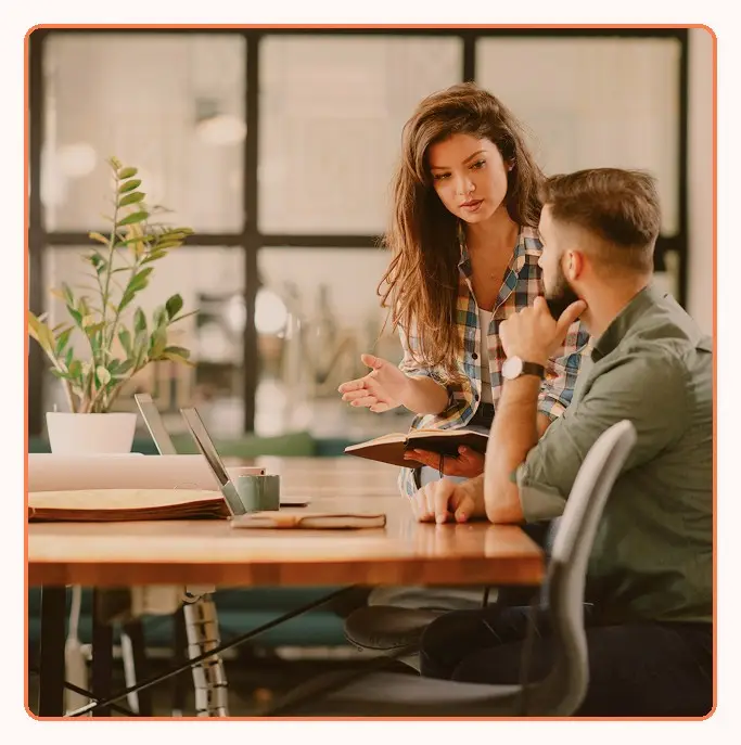 Two colleagues reviewing notes together at a table