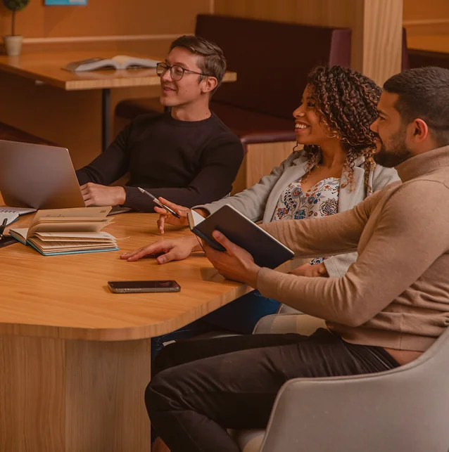 Colleagues talking around a table with laptops