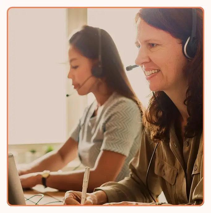 Two agents with headsets taking notes during calls