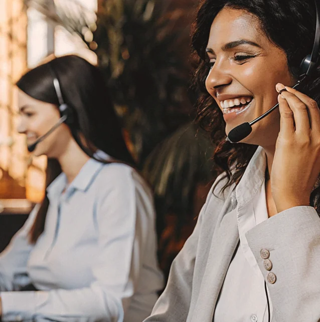 Two women wearing headsets, one smiling