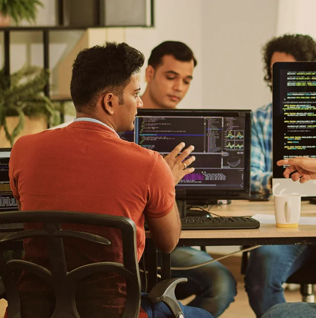 Several people working at computers with code on the screens