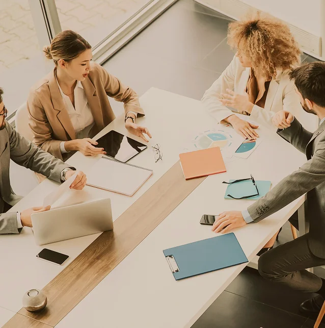 Overhead view of four people meeting at a table with laptops and folders