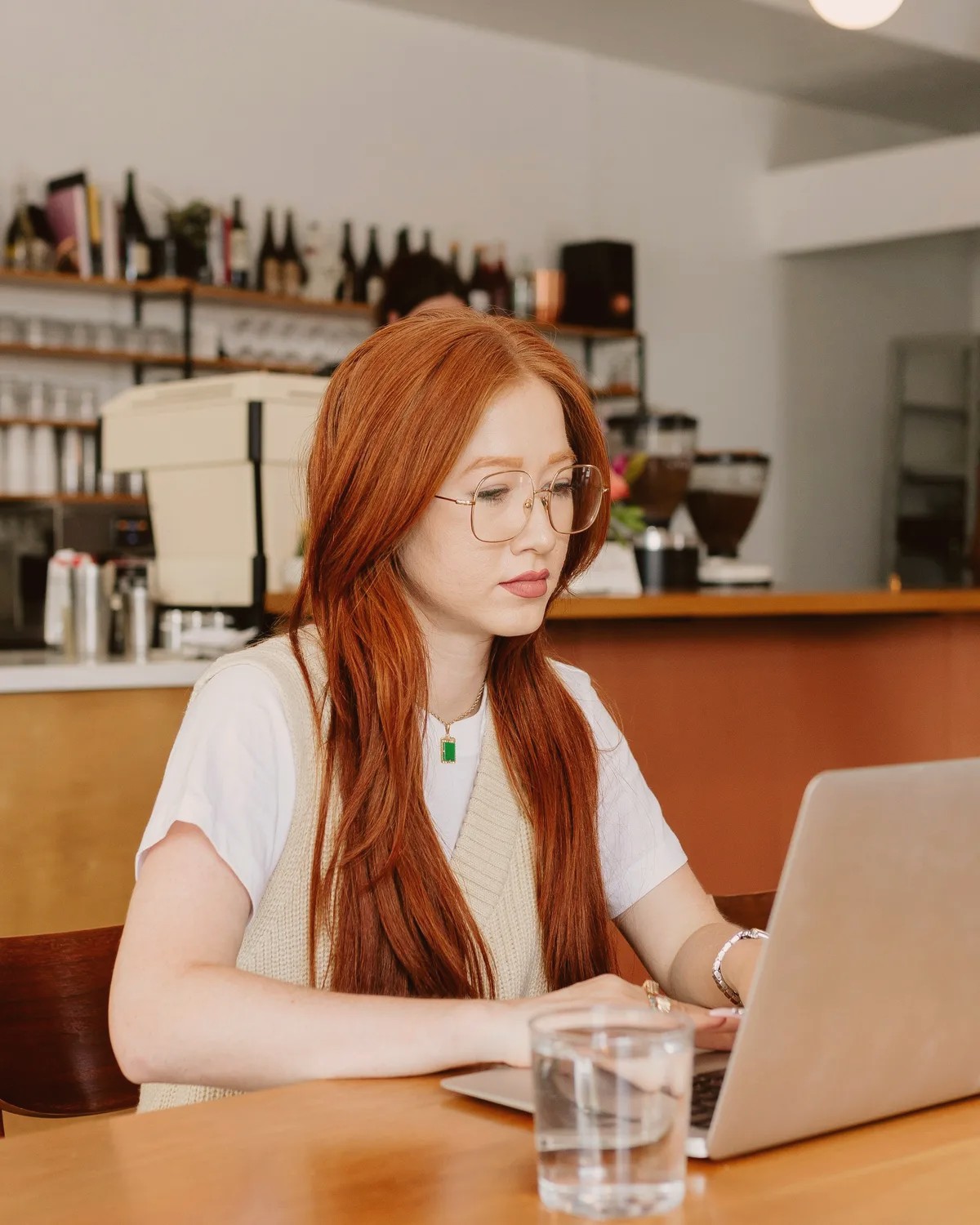 Woman with red hair working on a laptop in a cafe