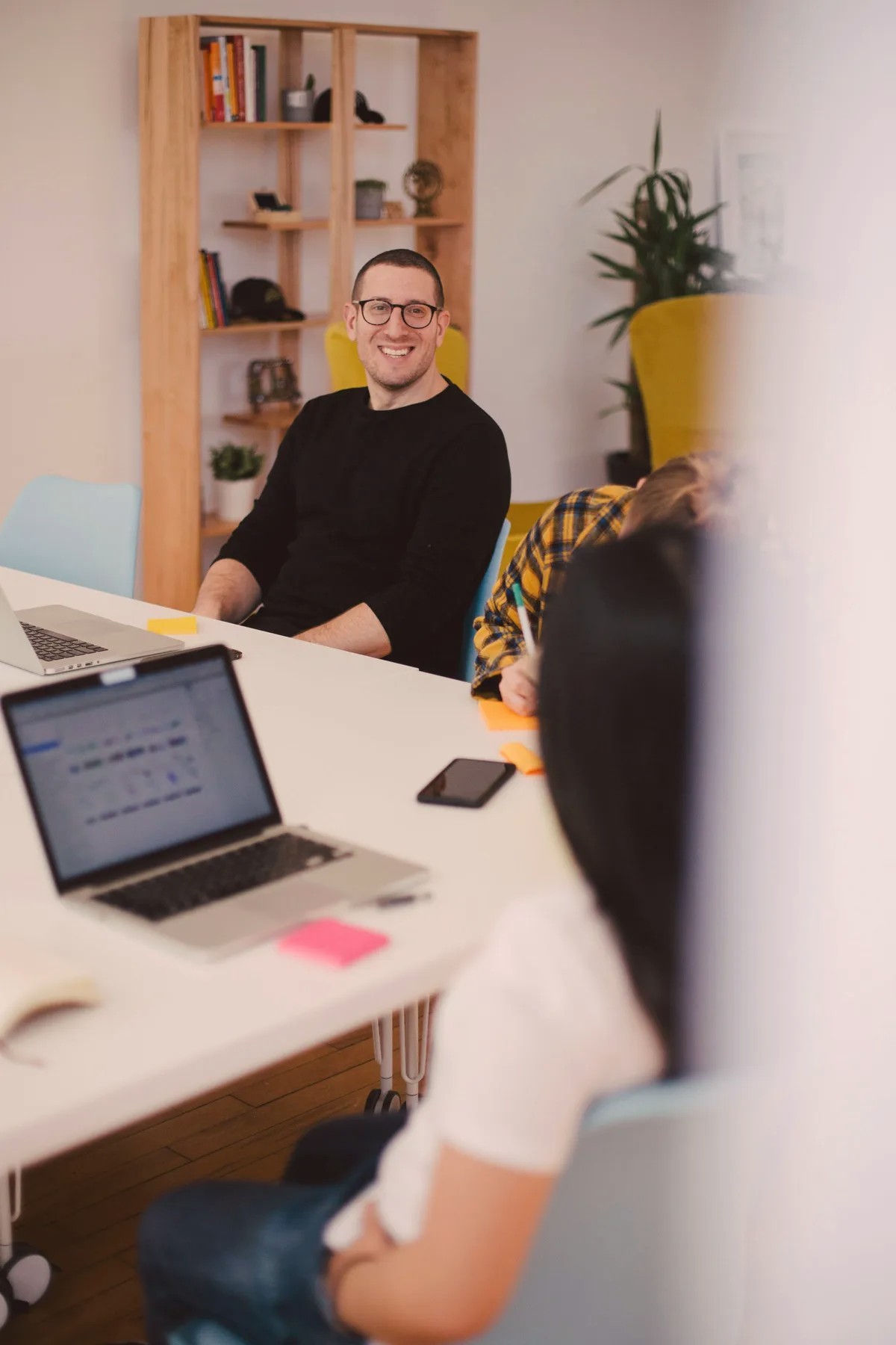 Man at a desk with a laptop, seen past a colleague in the foreground