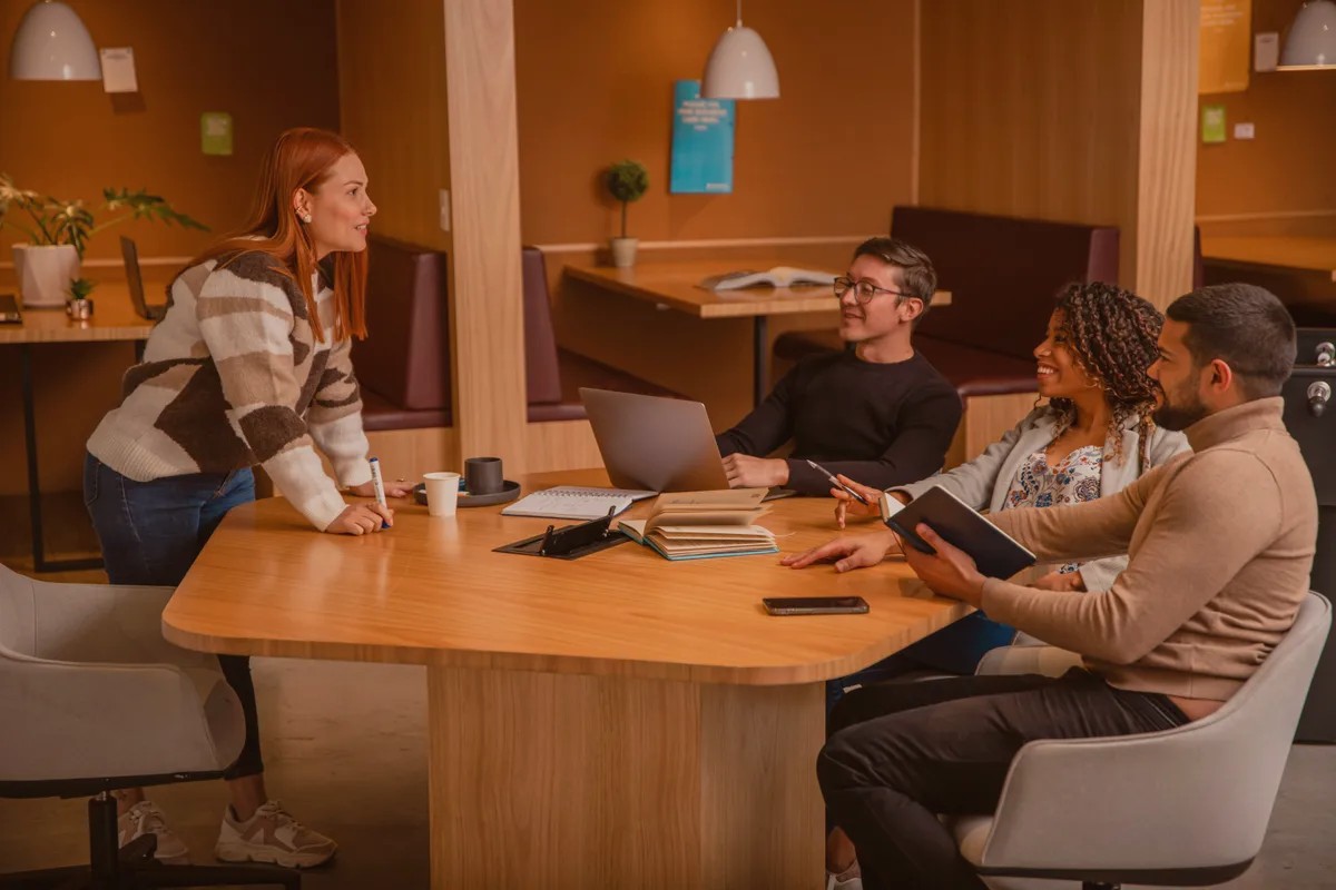 Colleagues talking around a wooden table in an office