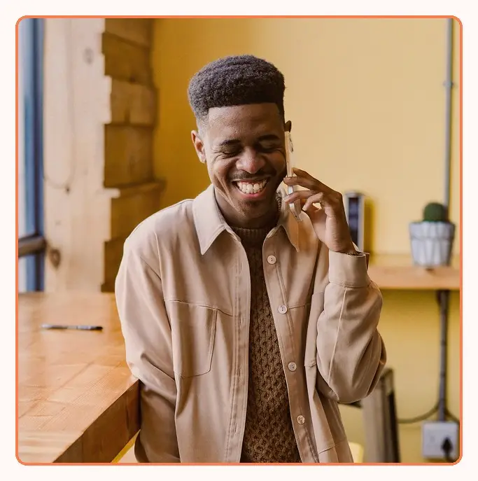 A man laughing during a phone call at a desk