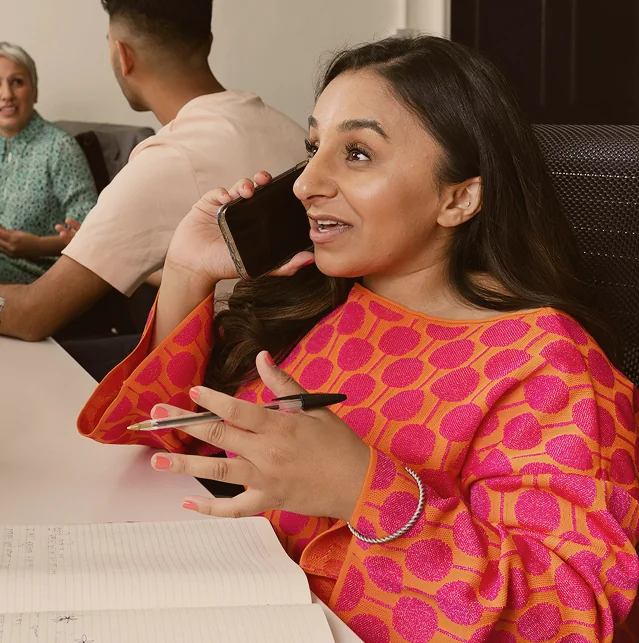 Woman in a pink patterned top talking on a mobile phone
