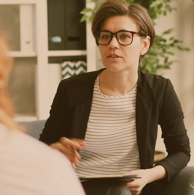 Woman in glasses talking to a colleague, holding a tablet