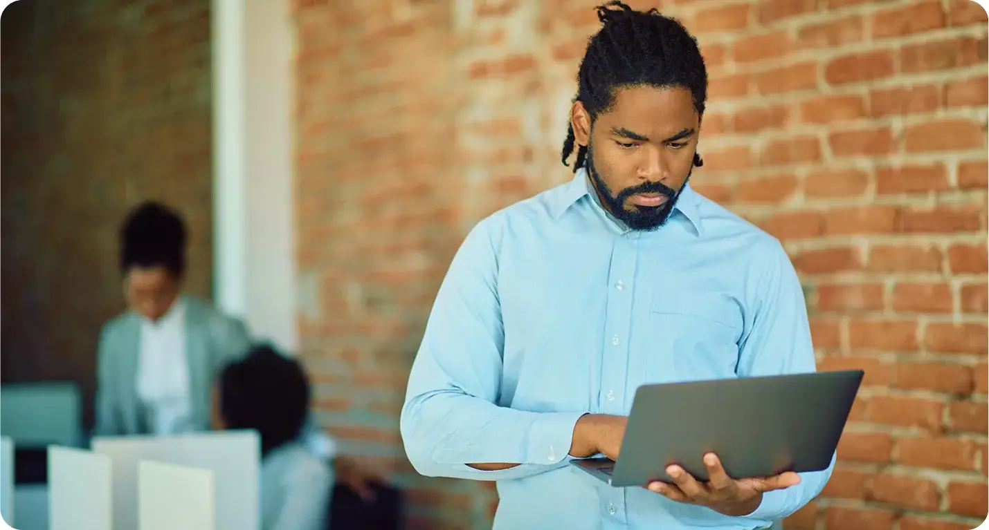A colleague reviewing work on a laptop while standing
