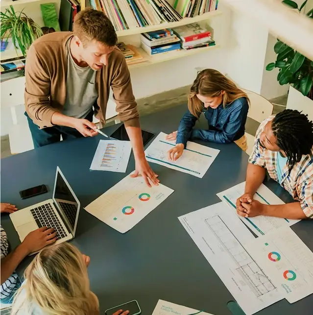 A team reviewing printed charts and reports around a meeting table