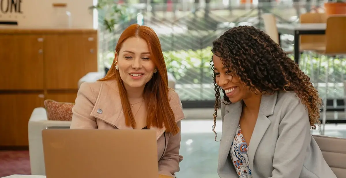 Two colleagues reviewing figures together on a laptop